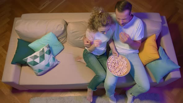 Happy Couple Eating Popcorn and Watch Movie on the Sofa