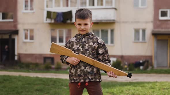 Portrait of Young Ukrainian Boy in Camouflage with Wooden Gun