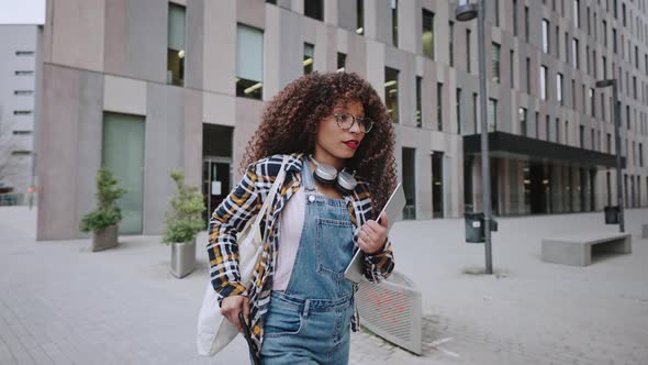 Beautiful African American Woman with Curly Hair Wearing the Shirt and Jeans Hurries Up to the