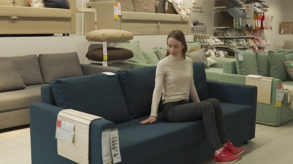 Female Customer Choosing Sofa in Shopping Center