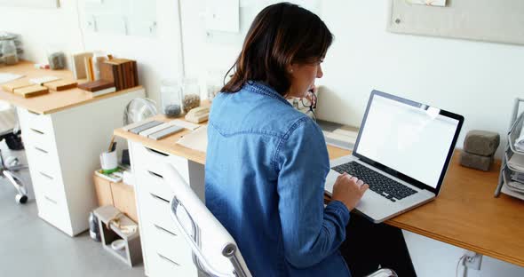 Female executive sitting at desk and using laptop