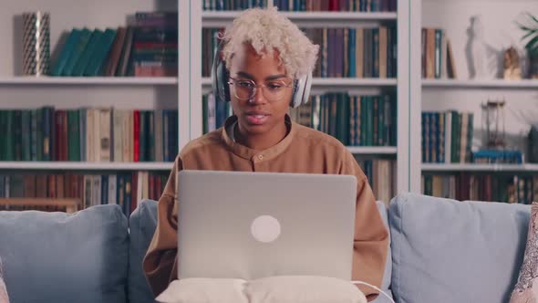African Woman in Headset Looking at Laptop Holding Web Call with Colleagues