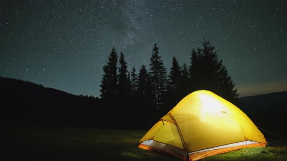 Time Lapse of Brightly Illuminated Camping Tent Glowing on Campsite in Dark Mountains Under Night