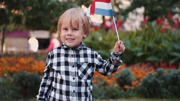 Little Boy in Checkered Shirt Holding Flag of Netherlands