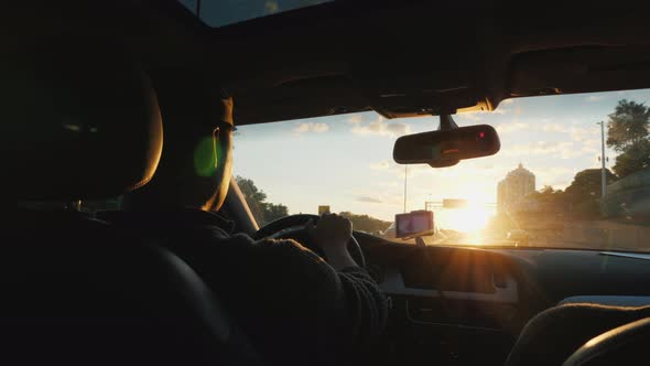 Young Driver Driving a Car. Sunset Rear View