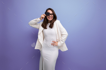 portrait of a young woman with dark hair in a white dress holding a money card for shopping