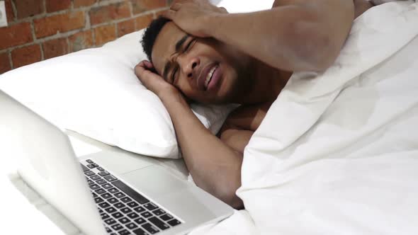 African Man in Bed Reacting to Loss and Failure on Laptop