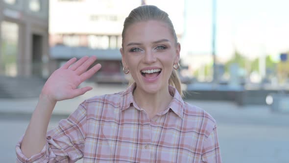 Welcoming Young Woman Waving Hand for Hello Outdoor