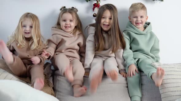 Friendly Children Sit on the Back of the Sofa and Play Near the Christmas and New Year Decorations