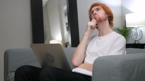 Pensive Redhead Man Working on Laptop in Bedroom