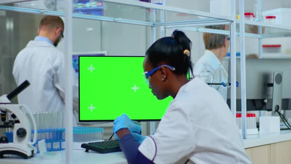 African Doctor Working at Computer with Green Screen