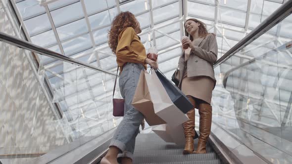 Attractive Women Going down on Escalator in Shop