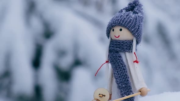 Angel Gnome in Scarf and Knitted Hat Skiing on Snowy Fir Branch Elf Toy on Skis in Snowy Landscape