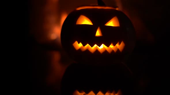 Creepy halloween pumpkin near a fireplace. Fire on the background.