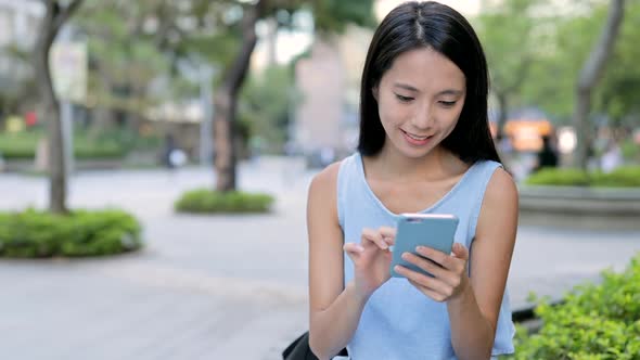 Woman Looking at Mobile Phone in City