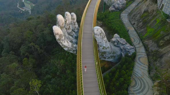 Aerial shot of a young woman walking on the Golden Bridge in the city of Danang