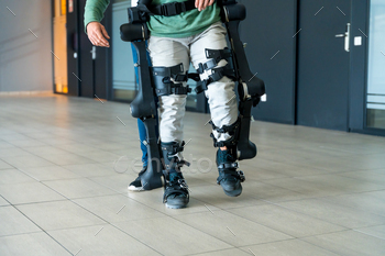 Mechanical exoskeleton, physiotherapist walking with unrecognizable disabled with robotic skeleton