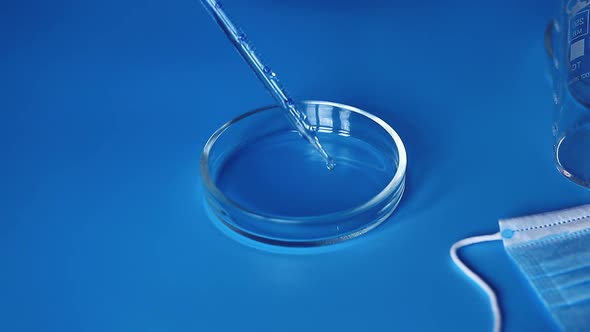 Doctor drops the sample into a test tube with a pipette on a blue background.