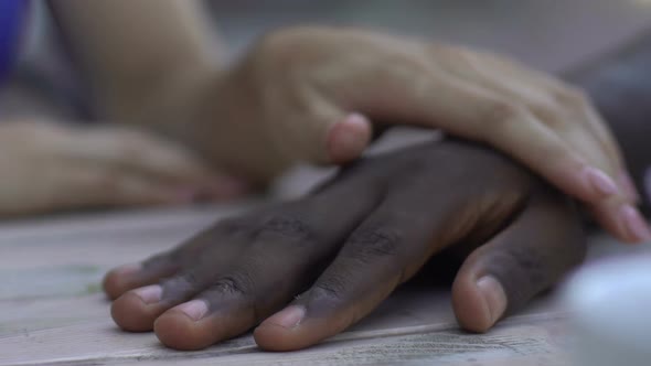 Caucasian Woman Holding Hand of Her African-American Boyfriend, Tenderness