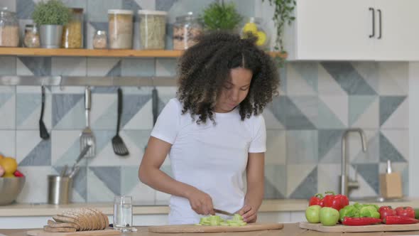 Young African Woman Cutting Vegetables in Kitchen