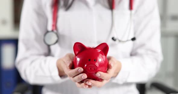Doctor Holding Red Piggy Bank in Clinic Closeup  Movie Slow Motion
