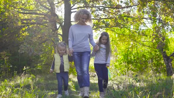 Happy Caucasian Family Strolling in the Sun Rays in the Autumn Park