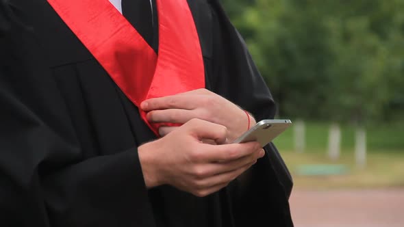 Male Graduate Watching Video Greetings on Smartphone, Checking Social Networks