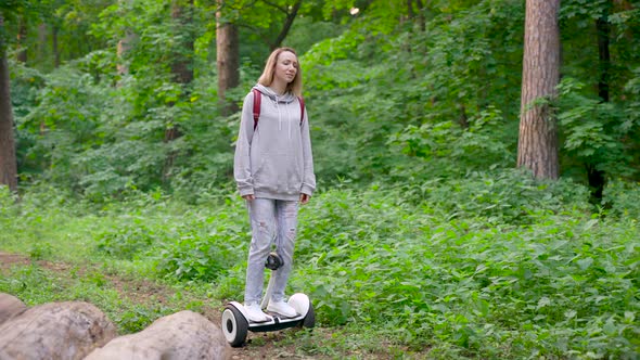 A Beautiful Girl Rides in the Woods on a Gyrocopter. A Girl in Jeans, with a Red Backpack