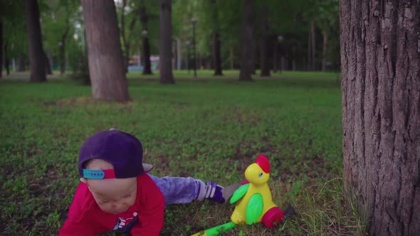 The Boy Runs with a Toy and Falls on the Grass in the Park. Baby Upset, Slow Motion