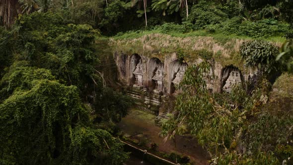 Rock-cut shrines carved into cliff at Kawi Sebatu Hindu temple, Ubud; drone