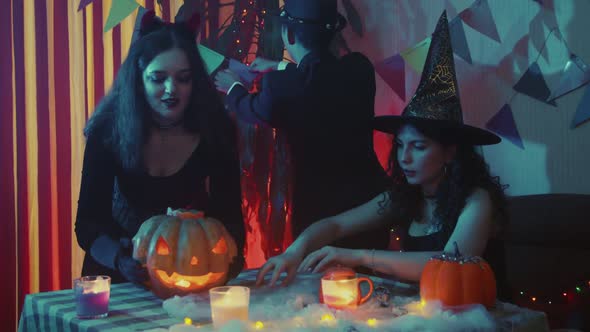 A Group of Friends in Creepy Costumes Decorate the Room for Halloween