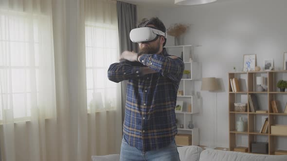 Young Caucasian Man Wearing Virtual Reality Glasses Dancing at Home in the Living Room