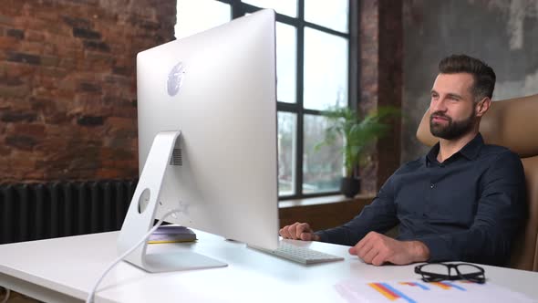 Male Office Employee Using Computer App for Video Connection with Colleagues on Distance