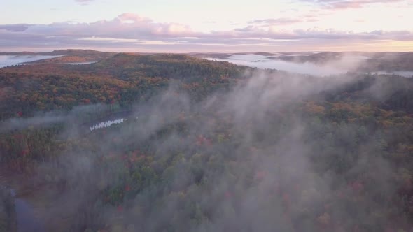 Aerial Sunrise Wide Shot Flying Through Cloud Fog Over Misty Lakes And Fall Forest Colors Pans Right