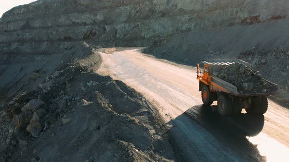 Career dump truck goes in a gold mine. Open pit mine quarrying extractive industry stripping work.