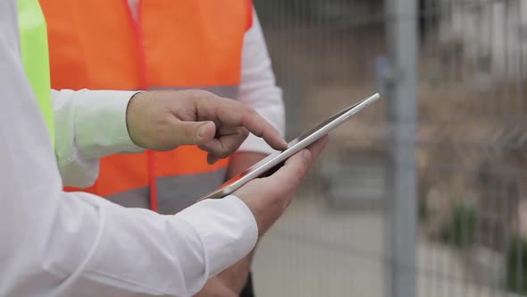 Close Up of Architect Hands Using Tablet Near Construction Site. The Builder and Architect Man Are