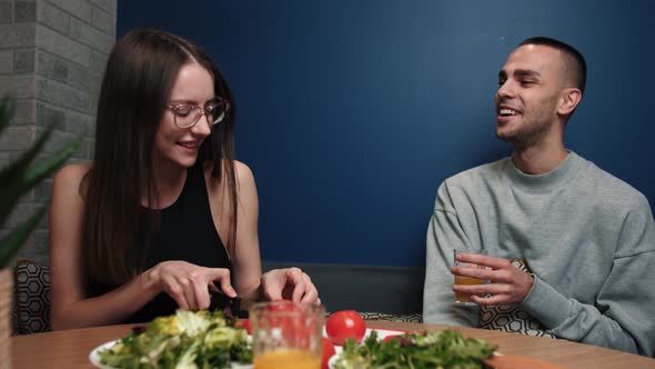 Young Happy Couple Cooking Together Preparing Dinner Chopping Vegetables and Talking at Home