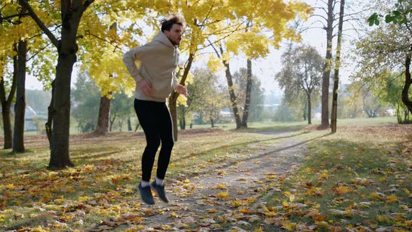 Man Doing Exercises and Stretching Before Morning Run at the Park in Autumn