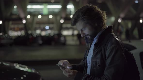Happy Young Man Chatting on Smartphone at Night