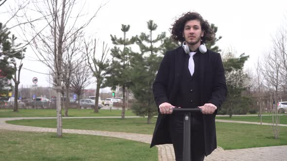 Young Modern Male Businessman Rides an Electric Scooter