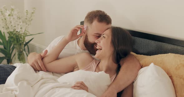 Man and Woman in Romantic Relationship Cuddling and Smiling While Lying on Bed in Morning, Couple