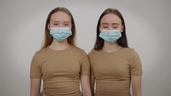 Identical Twins Posing in Covid19 Face Masks at Grey Background