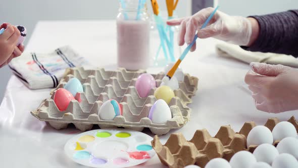 Little girl painting craft Easter eggs with acrylic paint.