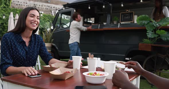 Multiracial friends eating at food truck table outdoor - Summer and lifestyle concept