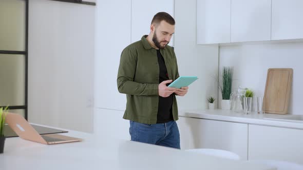 Confident Absorbed Man Entering Kitchen Holding Tablet Swiping Social Media