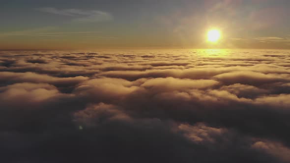 Flying Over Clouds Towards Sun on Background of Golden Sunset