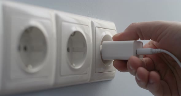 Hand Connecting Electric Plug Usb Charger Into A Wall Socket Concept Of Saving Energy