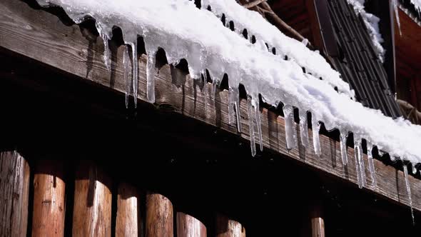 Icicles Melt and Dripping on the Sun Hanging on the Roof of Wooden House. Slow Motion