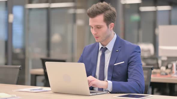Businessman Having Wrist Pain While Using Laptop in Office