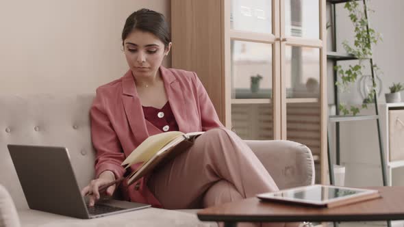 Mixed-race Businesswoman Working on Laptop and Making Notes